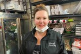 A woman with a face mask around her chin inside a florists