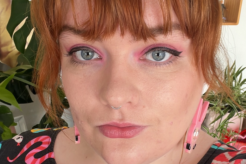 a woman with pink eye shadow and pink earrings 