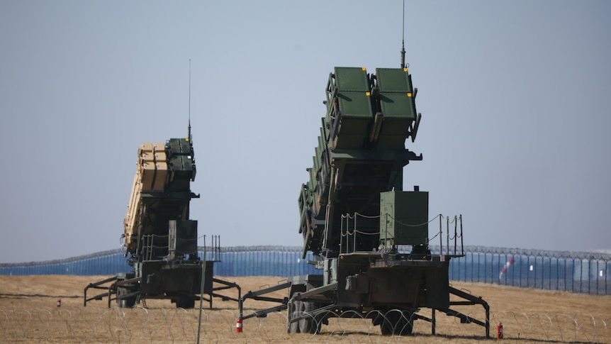 Two Patriot surface-to-air missile systems stand together in a test field.