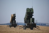 Two Patriot surface-to-air missile systems stand together in a test field.