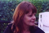 A smiling woman with dark, coppery hair.