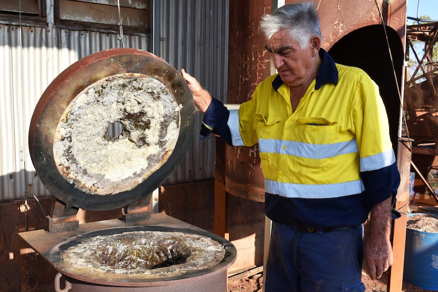 A man standing next to a diesel fired furnace looking into it.