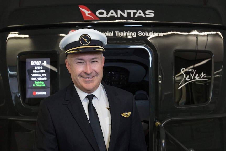 Sean Golding standing outside the door of a Qantas plane.