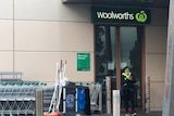 A cleaner stands outside a Woolworths store.