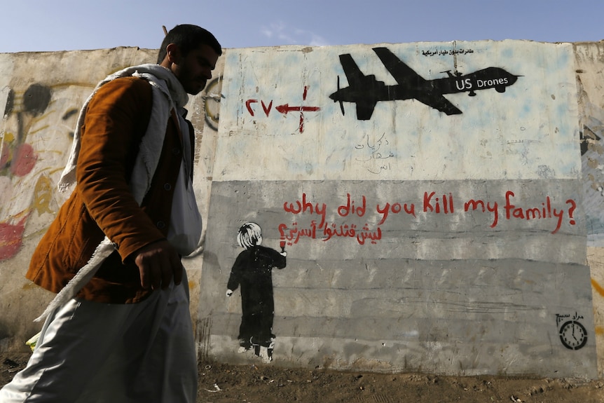 A man walks past graffiti denouncing strikes by United States drones in Sanaa.