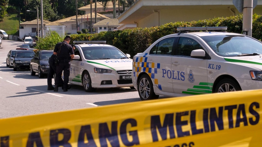 Police cars line the street behind a 'do not cross' tape.