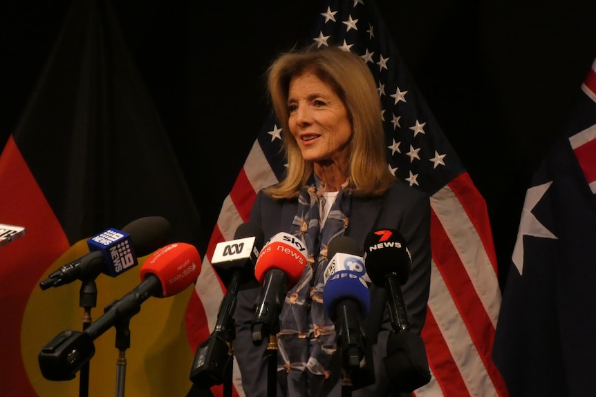 Caroline Kennedy speaks at a press conference in front of US, Australian and Aboriginal flags