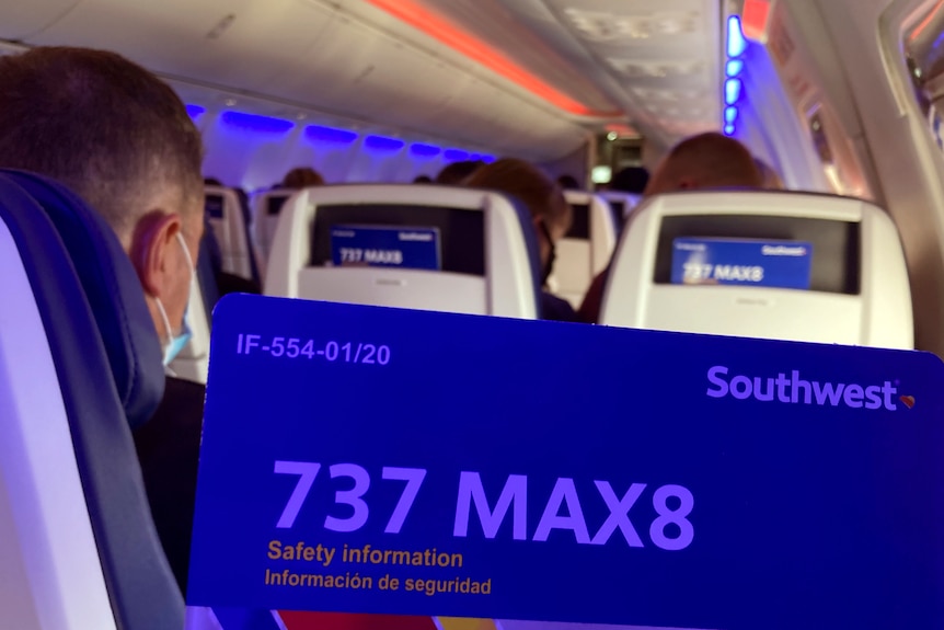people sit on an airplane with blue markings which read 737 MAX8