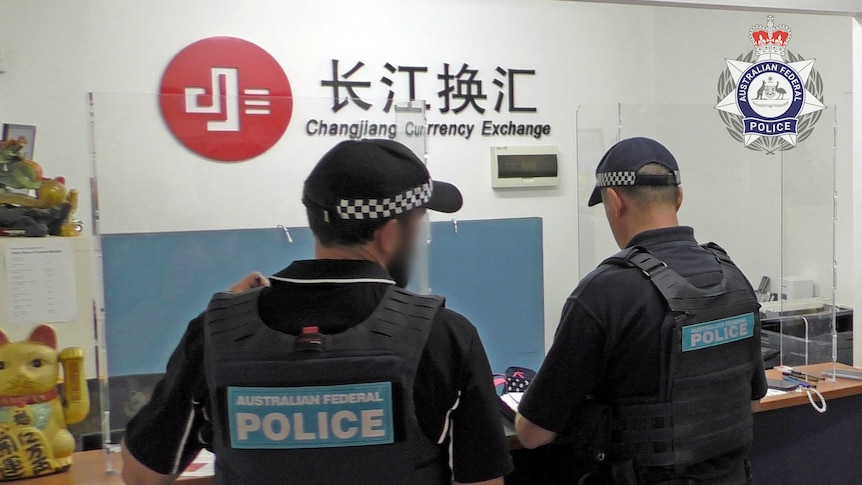 两名警察站在长江换汇门店中，墙上有长江换汇标识