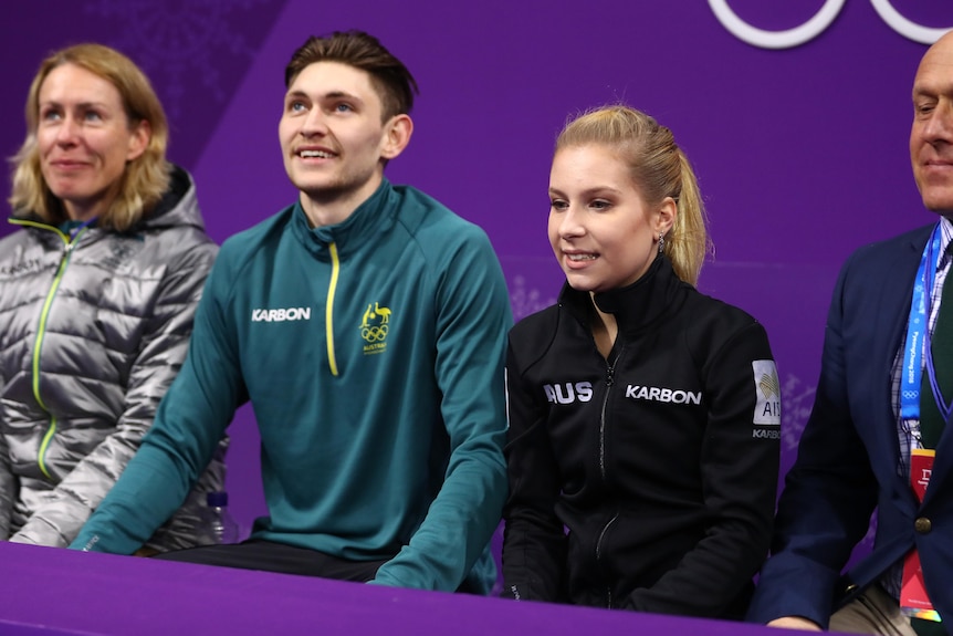 Two Australian figure skaters smile and look at the scoreboards after their performance at the Winter Olympics.