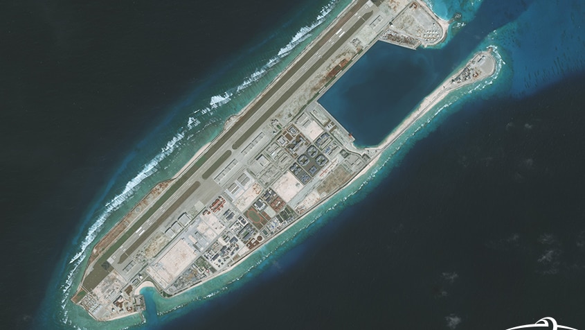 An aerial view of the Fiery Cross Reef surrounded by deep blue water.