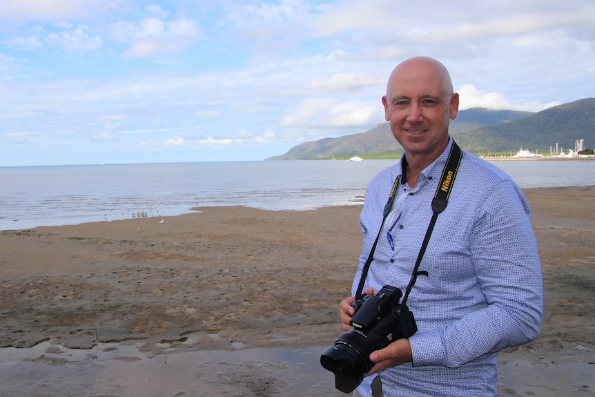 A man in a long sleeve blue shirt stands in fron 