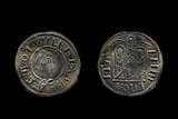 Two ancient looking coins on a black background