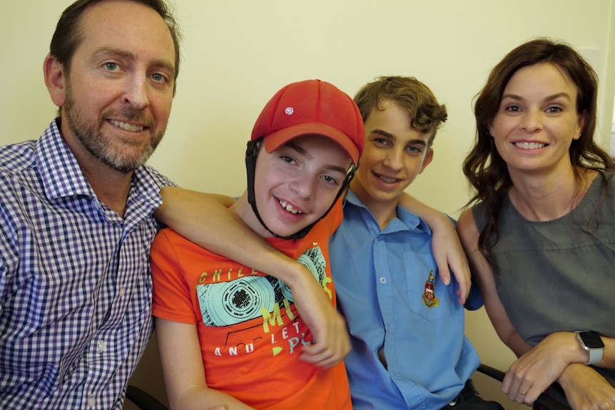 Two boys, a man and a woman sitting together smiling at the camera.