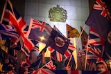 A crowd of protesters wave Britain's union jack flag and Hong Kong's British colonial flag in front of the British coat of arms.