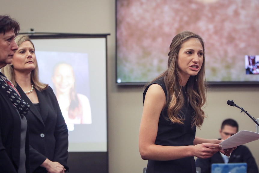 Kyle Stephens holds her victim impact statement and speaks into a microphone in a courtroom.