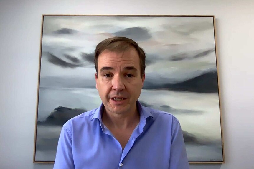 David Van Rooy sitting at an office desk with a grey and white picture behind his head.