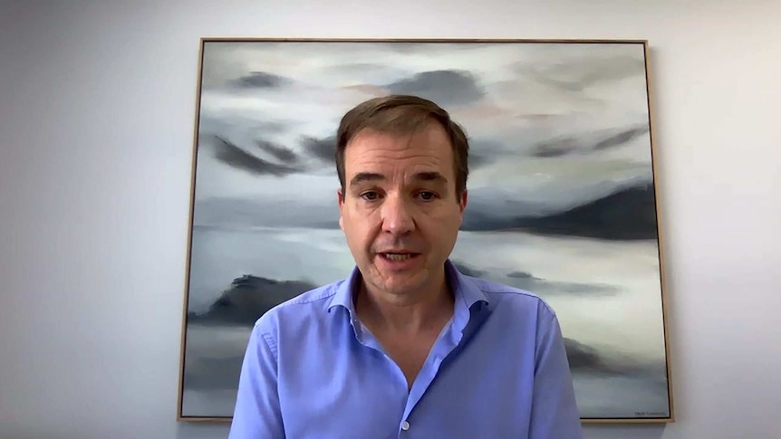 David Van Rooy sitting at an office desk with a grey and white picture behind his head.