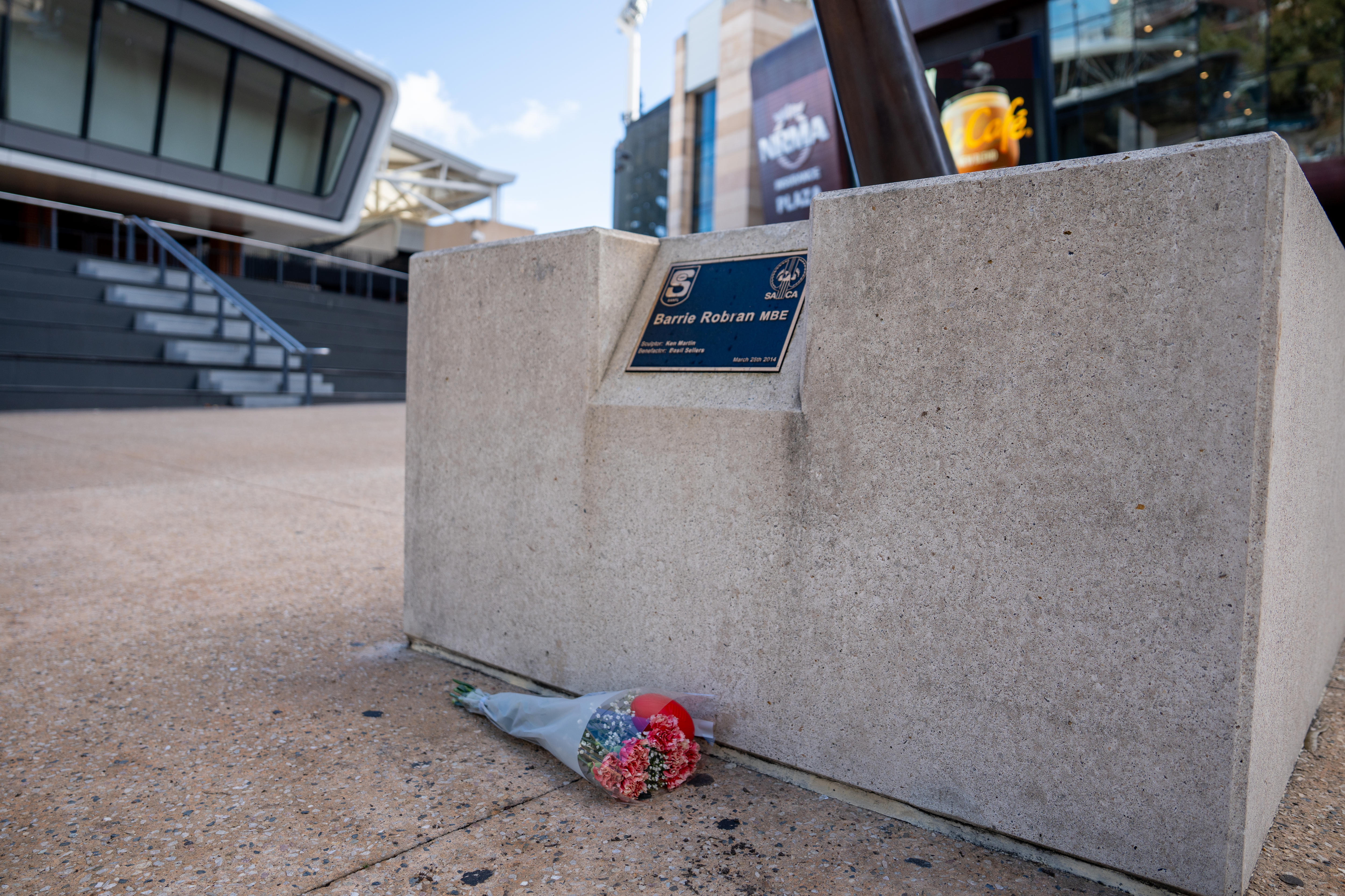 Flowers left at the base of the plinth of the statue of Barrie Robran.
