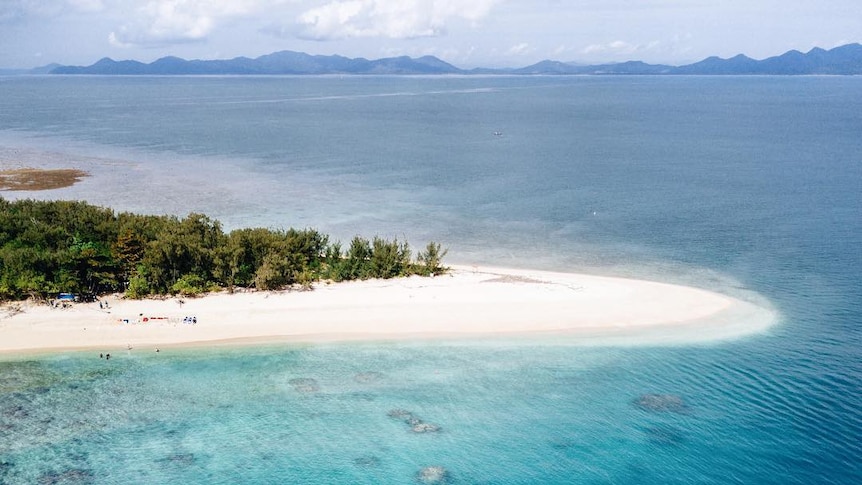 A drone photo of clear blue water and tropical coastline