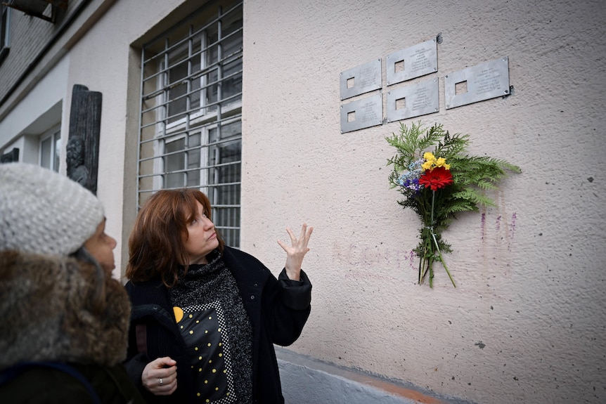 Oksana Motievskaya, coordinator of the Last Address Foundation, gesturing by metal plaques.