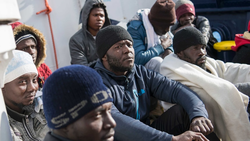 A group of men set on the deck of a ship staring out to sea.