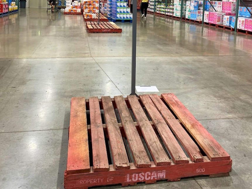 An empty wooden pallet that usually has piles of toilet paper on it.