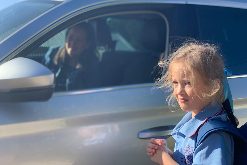 A young girl being dropped off at school by her mother