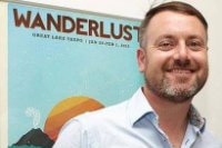 Headshot of Jonnie Halstead in front of Wanderlust poster