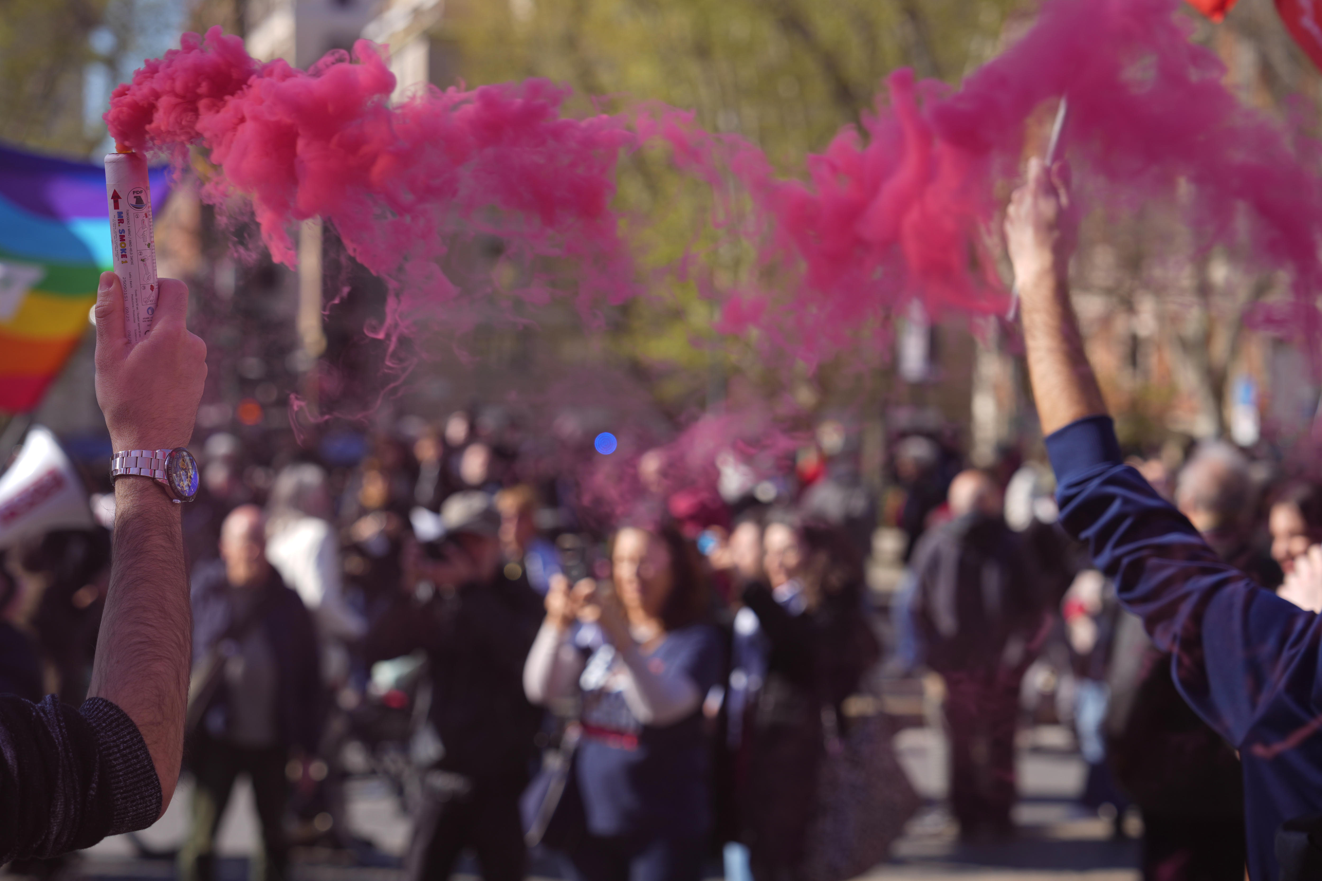 Two people hold up flares emitting a pink smoke at a rally in Rome.