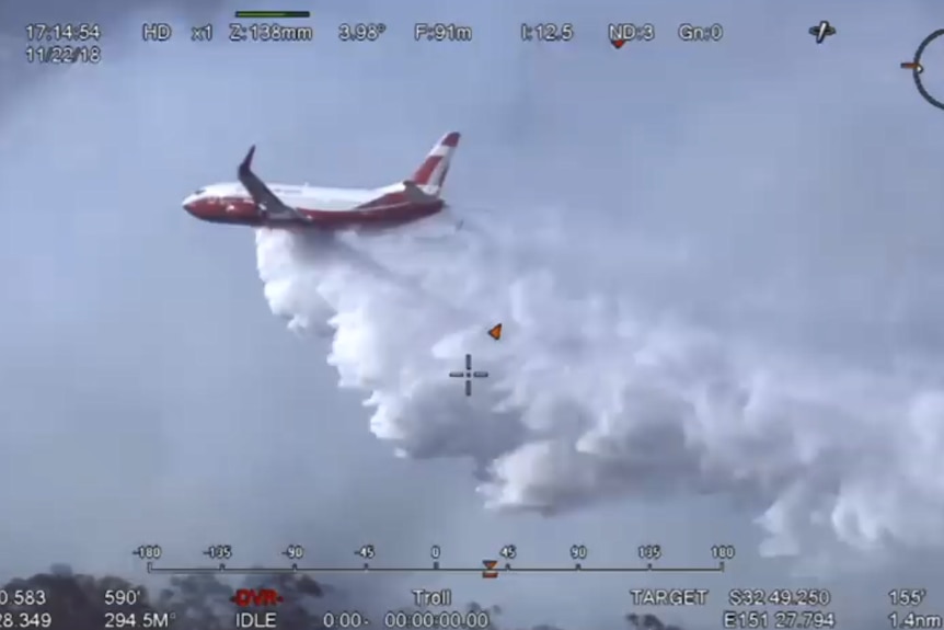 A jumbo-sized firefighting plane dumping retardant on a blaze.