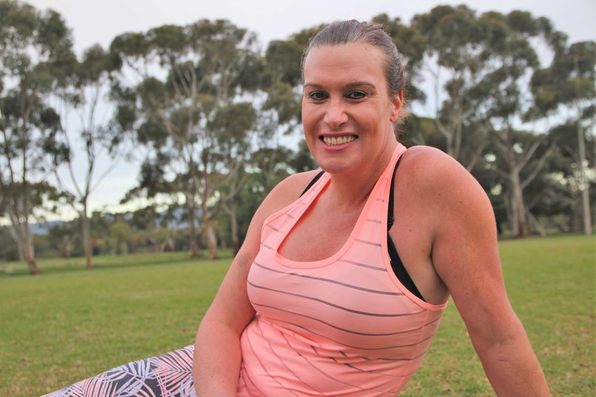 Lucy Finlay sitting on a football oval and smiling