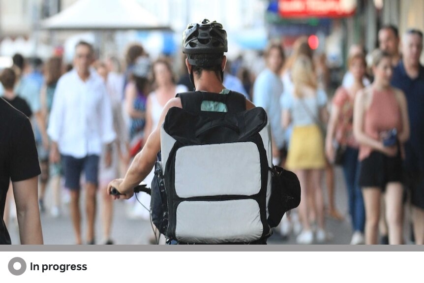 A hand holding a smartphone with a map on it attached to handlebars