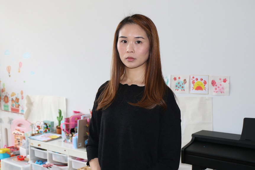 A young woman of Asian background standing in a living room