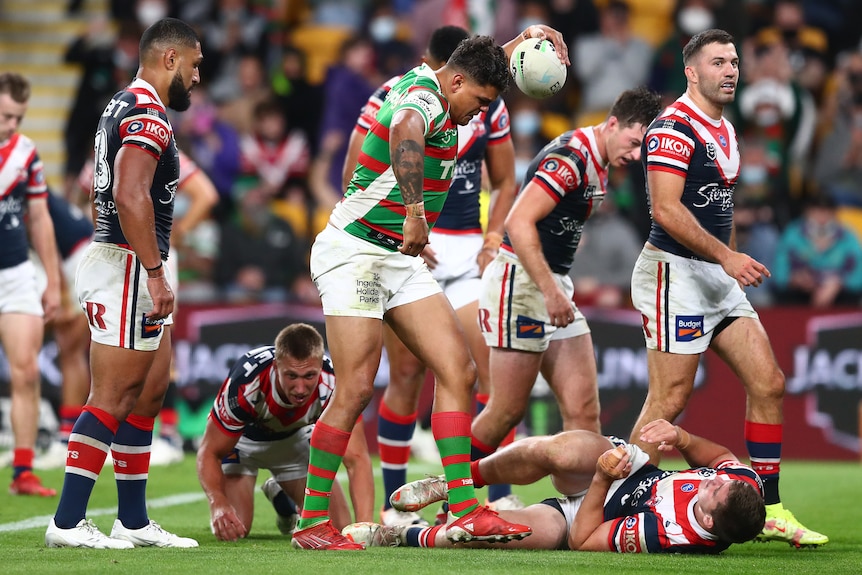 A South Sydney NRL player begins to throw the ball on the ground as he celebrates a try.