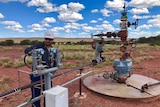 Man standing behind gas well checking valve.