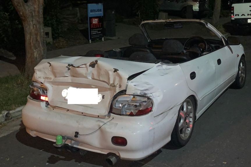 A white car with a damaged boot