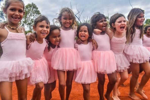 Close-up of young Aboriginal girls smiling and wearing pink dance costumes