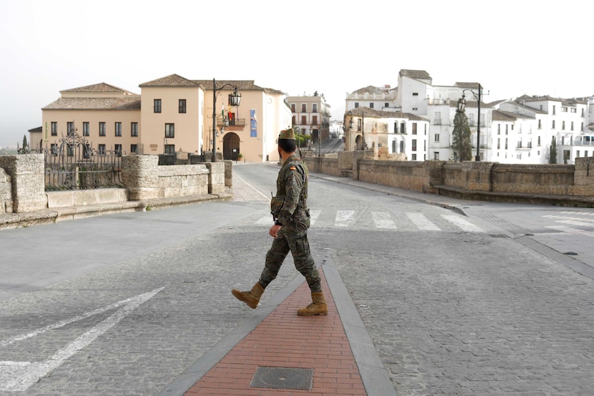 A Spanish legionnaire patrols an empty Spanish medieval village on an overcast day.