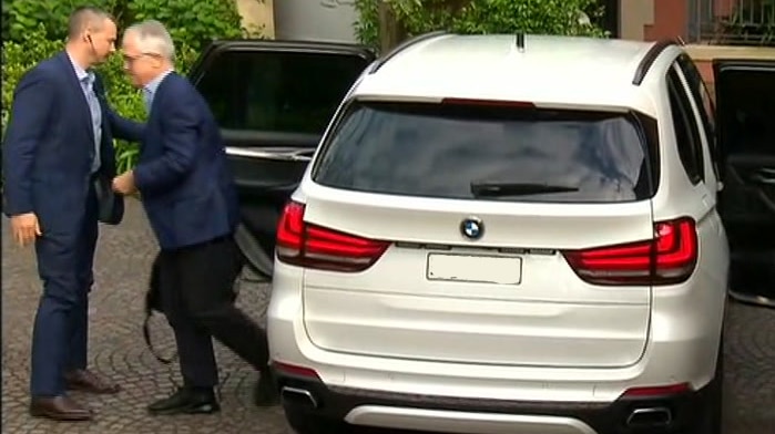 people leaving white car with security guards