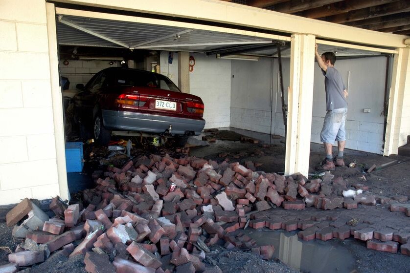 A car sits awkwardly in its garage at The Gap after being flung around by floodwaters.