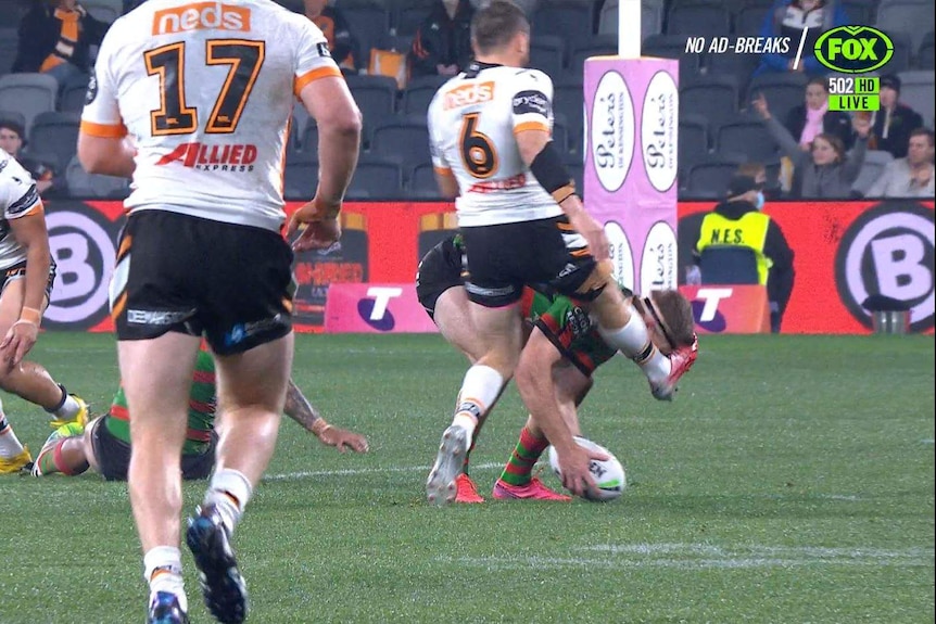 Wests Tigers' Josh Reynolds kicks South Sydney's Campbell Graham in the head as he picks the ball up during their NRL game.