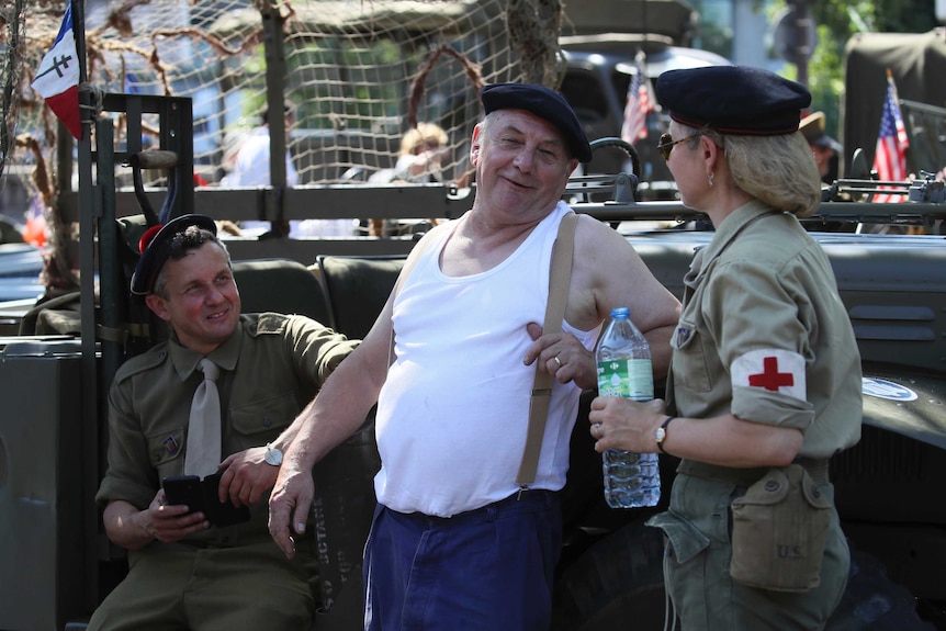 People dressed in World War II era clothes joke ahead of celebrations of the liberation of Paris.