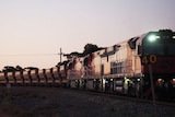 A train at sunset, full of iron ore on a remote track