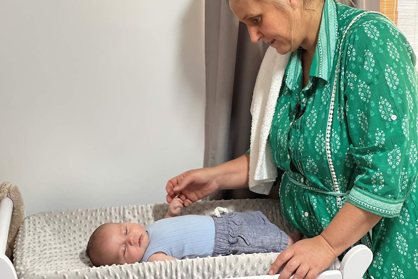 A mother look over her baby boy on a change table