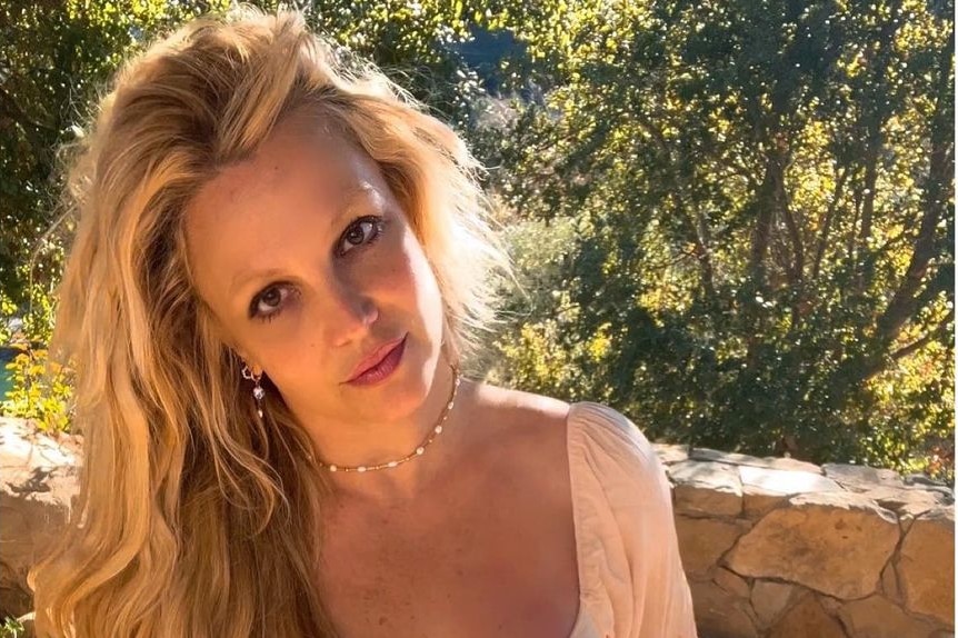 Britney Spears smiles angelically with her head tilted and her blond hair out