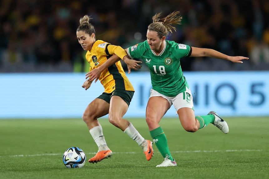 A Matildas defends the ball from an Irish player.