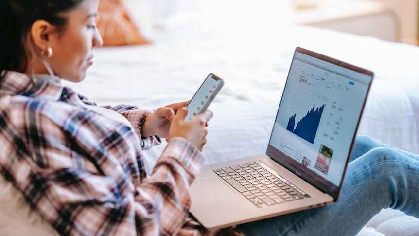 A woman looks at an investment chart on a laptop, in a story about what to consider when opening brokerage account.