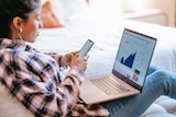 A woman looks at an investment chart on a laptop, in a story about what to consider when opening brokerage account.
