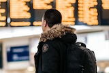 A man looks at flights in an airport, for a story about travel insurance and the novel coronavirus.